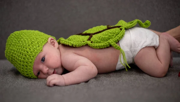 Bambino di tre mesi sdraiato su un divano e travestito da tartaruga verde . — Foto Stock