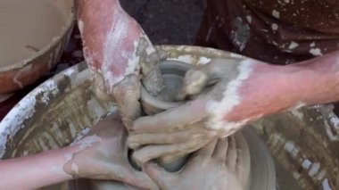 Potter torna üzerinde bir kil pot oluşturmak için elleri ile bir kız yardımcı olur