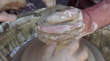 Potter torna üzerinde bir kil pot oluşturmak için elleri ile bir kız yardımcı olur