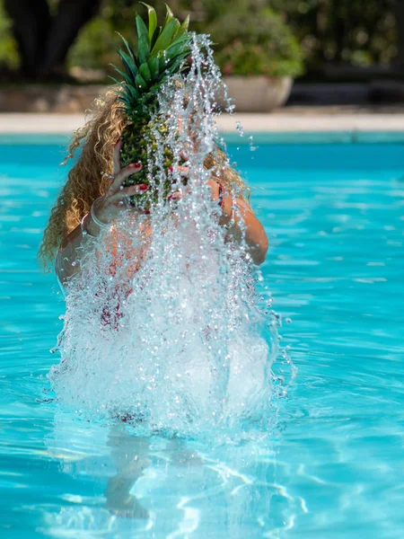 Menina loira branca brinca com um abacaxi na piscina . — Fotografia de Stock