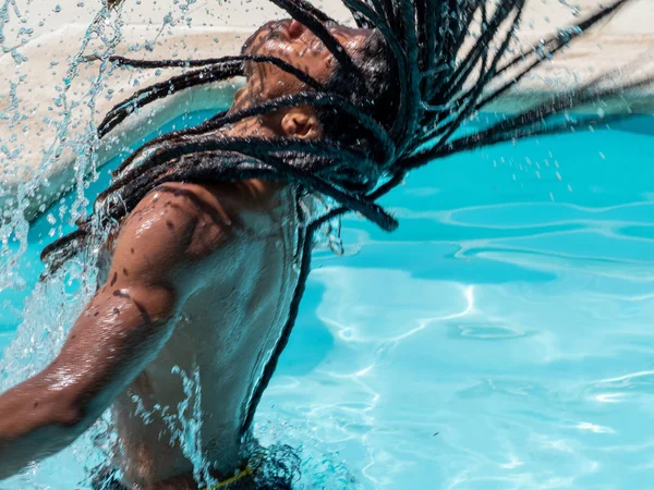 Czarny człowiek z Afro włosy i dredy wychodzi z basenu rozpryskiwania wody. — Zdjęcie stockowe