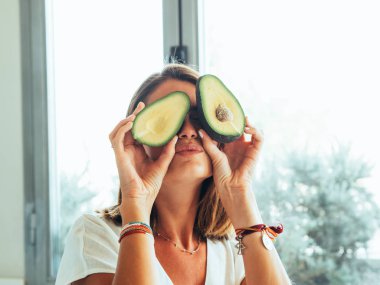 Modern mutfakta yeşil gözlü sarışın kadın parçası bir avokado gözleri ve baş koyarak oynamak için