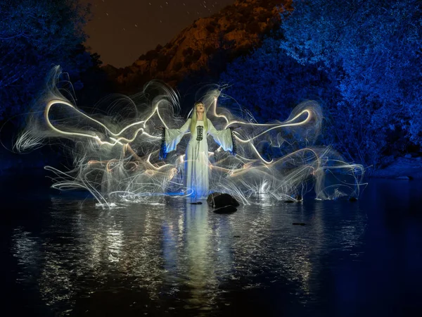 Nattlig fotografering, ljus målning, som representerar en modell i floden med skuggor gjorda med lyktor på floden — Stockfoto