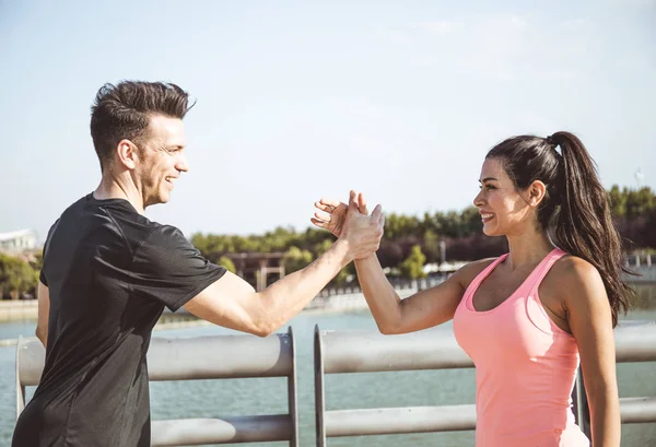 Caucasian man and Latin woman greet each other before they start doing sports on the side of a lake in a park in the city of Madrid