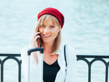 Kırmızı bereli beyaz kız, Madrid,İspanya'daki Parque del Retiro'nun göl çitinin yanında telefonda konuşuyor..