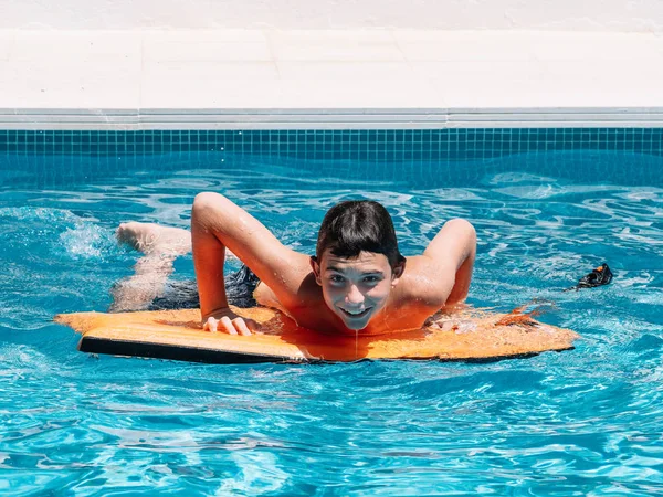 プレティーンは、彼らのバランスを保つために小さなサーフボードにジャンプしてプールで遊びます. — ストック写真
