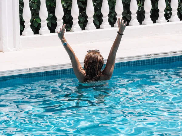 Achteraanzicht van een vrouw in een zwembad tijdens een zonnige zomerdag — Stockfoto