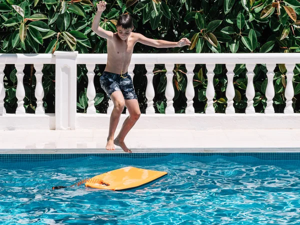 プレティーンは、彼らのバランスを保つために小さなサーフボードにジャンプしてプールで遊びます. — ストック写真