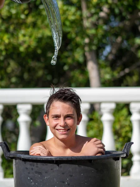 バケツの中で十代の少年の顔を叩いて水の衝撃を捉える高速写真. — ストック写真