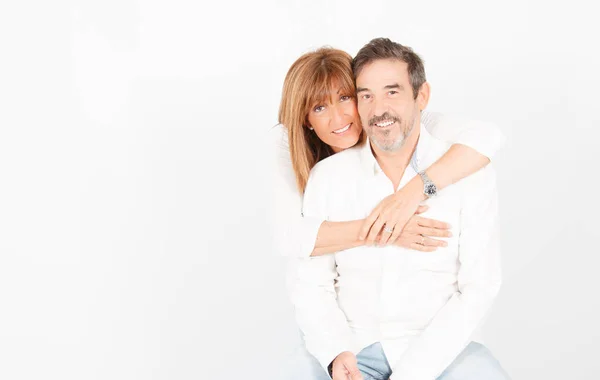 Un couple adulte de 50 ans pose dans un studio photographique d'une manière joyeuse avec un fond blanc . — Photo