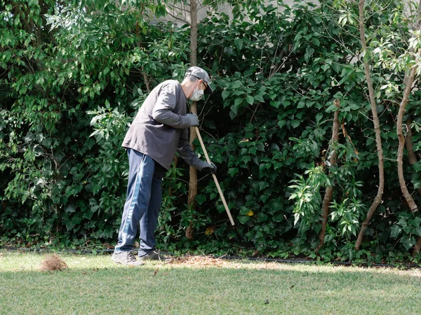 庭師の格好をした男の写真は 熊手で庭で仕事をしている — ストック写真