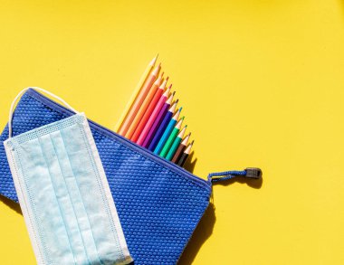 Çocuk çantasıyla renkli bir görüntü, renkli kalemler ve maske. Okula geri dön.