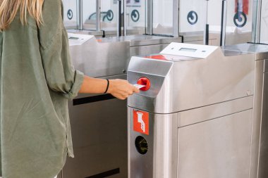 Tanımlanamayan bir kadın kapı makinesine kart atıyor ve modern tren istasyonundan bilet alıyor.