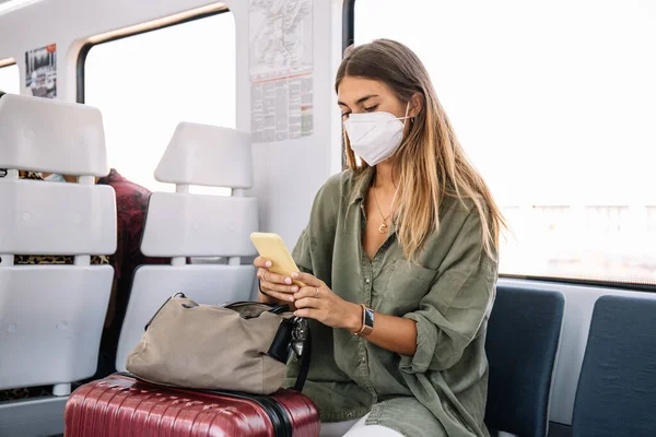 Giovane Viaggiatrice Maschera Medica Con Valigia Che Guarda Allo Smartphone — Foto Stock