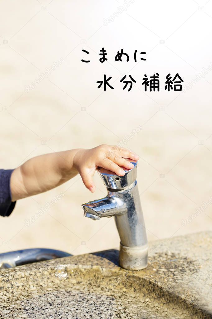 public drinking fountain with child's little hand in city park in summer.and japanese.