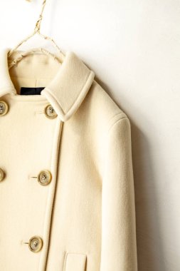 Beyaz arka plan üzerinde elbise askısı asılı beyaz yün ceket. Yakın çekim