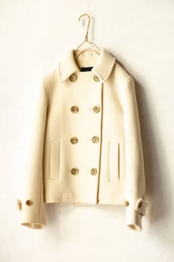 Beyaz arka plan üzerinde elbise askısı asılı beyaz yün kısa ceket