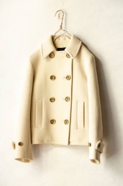 Beyaz arka plan üzerinde elbise askısı asılı beyaz yün kısa ceket