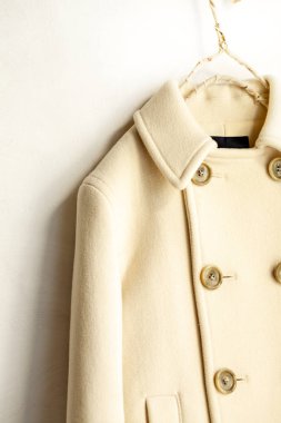 Beyaz arka plan üzerinde elbise askısı asılı beyaz yün ceket. Yakın çekim