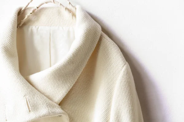 Abrigo de lana blanca colgando de la percha de ropa sobre fondo blanco — Foto de Stock
