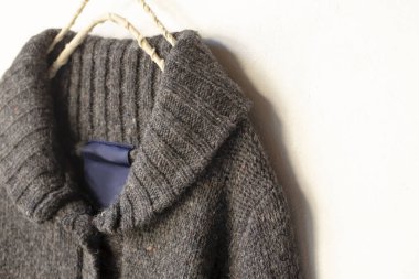 Beyaz arka plan üzerinde elbise askısı kahverengi asılı içinde kalın Örme Hırka.