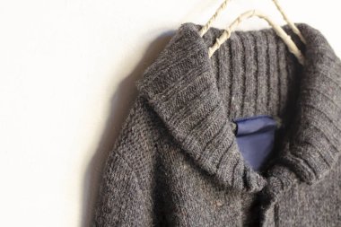 Beyaz arka plan üzerinde elbise askısı kahverengi asılı içinde kalın Örme Hırka.