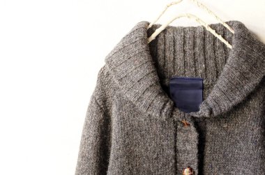 Beyaz arka plan üzerinde elbise askısı kahverengi asılı içinde kalın Örme Hırka.