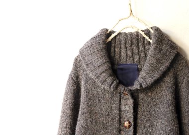 Beyaz arka plan üzerinde elbise askısı kahverengi asılı içinde kalın Örme Hırka.