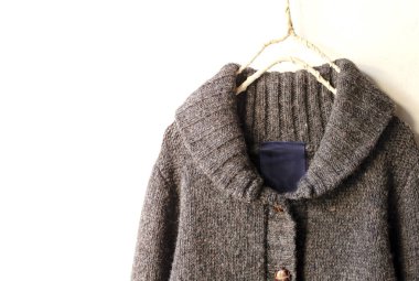 Beyaz arka plan üzerinde elbise askısı kahverengi asılı içinde kalın Örme Hırka.