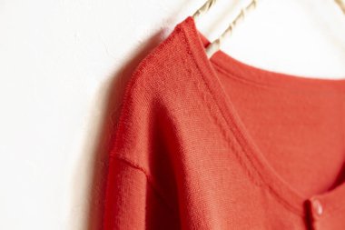 Beyaz arka plan üzerinde elbise askısı Turuncu pembe asılı bir hırka.