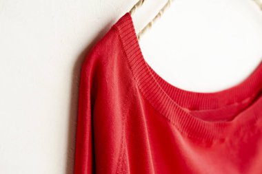 bir kesim sew veya örgü içinde kırmızı beyaz arka plan üzerinde elbise askısı üzerinde asılı.