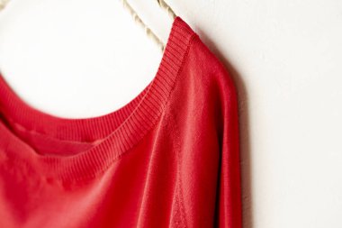 bir kesim sew veya örgü içinde kırmızı beyaz arka plan üzerinde elbise askısı üzerinde asılı.