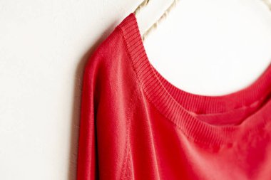 bir kesim sew veya örgü içinde kırmızı beyaz arka plan üzerinde elbise askısı üzerinde asılı.