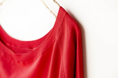 bir kesim sew veya örgü içinde kırmızı beyaz arka plan üzerinde elbise askısı üzerinde asılı.