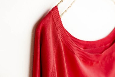 bir kesim sew veya örgü içinde kırmızı beyaz arka plan üzerinde elbise askısı üzerinde asılı.