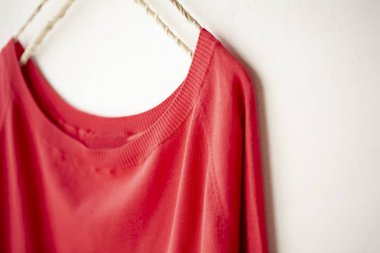 bir kesim sew veya örgü içinde kırmızı beyaz arka plan üzerinde elbise askısı üzerinde asılı.