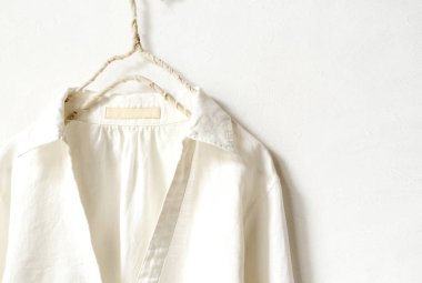 bir bluz ya da gömlek elbise askısı beyaz arka plan üzerinde beyaz asılı olarak. Yakın çekim.