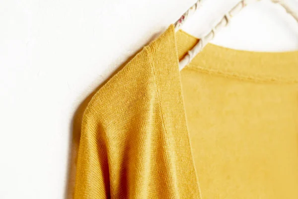 Un cárdigan en amarillo colgando de la percha de ropa sobre fondo blanco . — Foto de Stock
