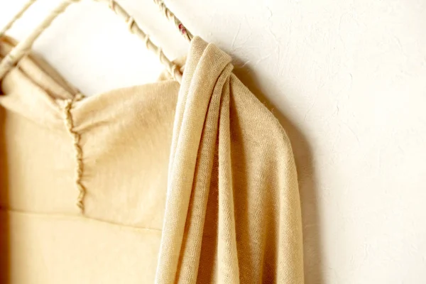 Un cárdigan en beige colgando de la percha de ropa sobre fondo blanco . — Foto de Stock