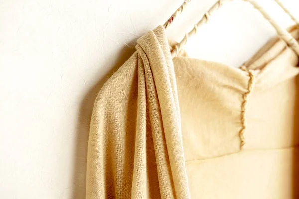 Un cárdigan en beige colgando de la percha de ropa sobre fondo blanco . — Foto de Stock