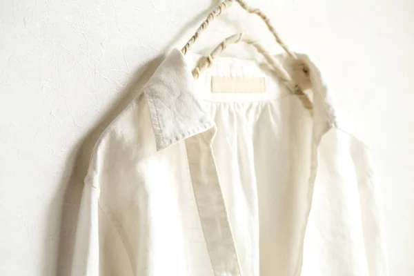 Een blouse of overhemd in wit opknoping op kleding hanger op witte achtergrond. Close-up. — Stockfoto