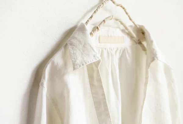 Una blusa o camisa en blanco colgando de la percha de ropa sobre fondo blanco. . — Foto de Stock