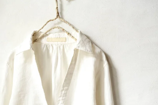 Блузка или рубашка в белом висит на вешалке одежды на белом фоне. Закрыть . — стоковое фото
