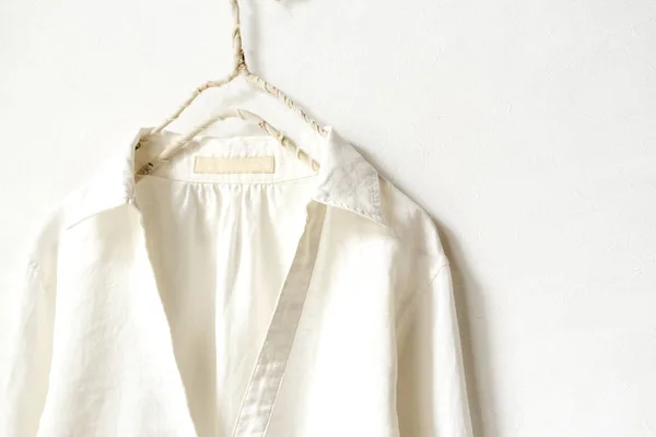 Una blusa o camisa en blanco colgando de la percha de ropa sobre fondo blanco. . — Foto de Stock