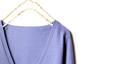 mavi yün kazak beyaz arka plan üzerinde giysi askısı asılı