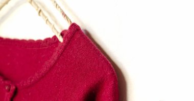 beyaz arka plan üzerinde giysi askısı asılı kırmızı bir hırka.