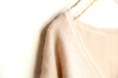 beyaz arka plan üzerinde giysi askısı asılı açık pembe kazak.