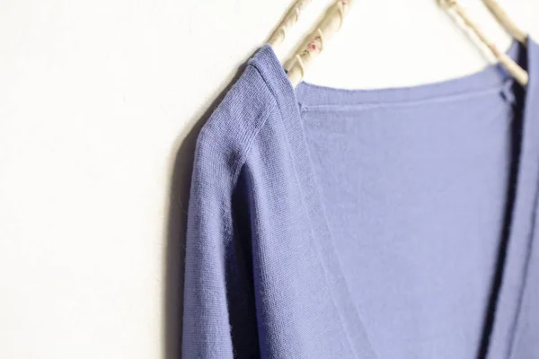Suéter de lana azul colgando de la percha de ropa sobre fondo blanco — Foto de Stock