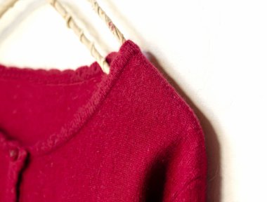 beyaz arka plan üzerinde giysi askısı asılı kırmızı bir hırka.