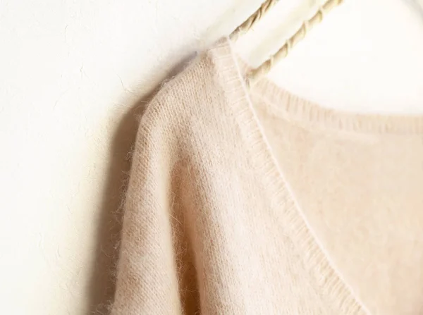 Suéter rosa claro colgando de la percha de ropa sobre fondo blanco . — Foto de Stock